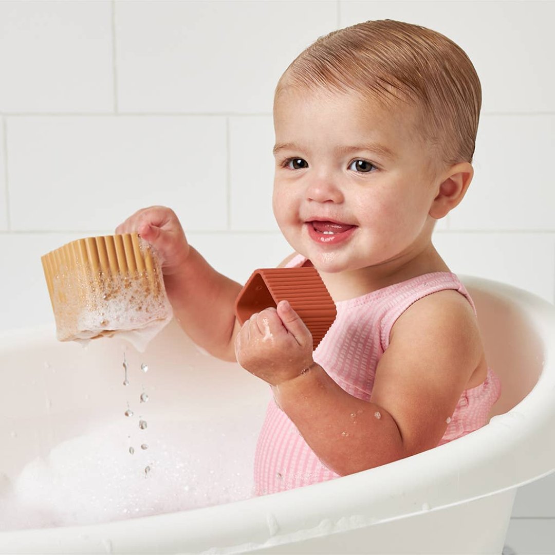 baby girl playing with 2 stacking blocks that are dripping water