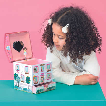 Child playing with a toy music box against a pink background