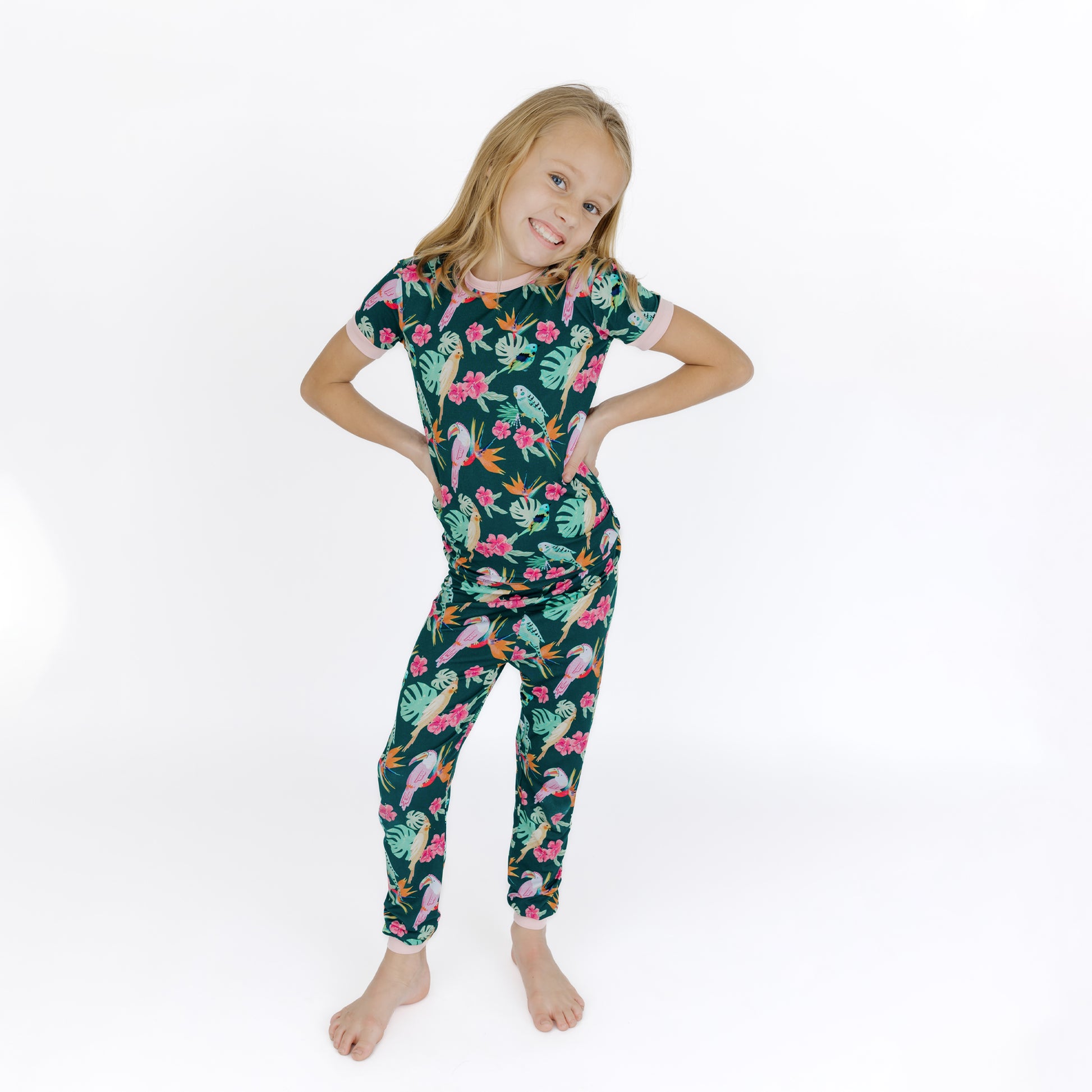 A young girl standing while wearing the Isla Botánica botanical print bamboo pajamas, showing the stretchy and snug fit.