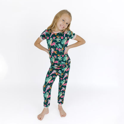 A young girl standing while wearing the Isla Botánica botanical print bamboo pajamas, showing the stretchy and snug fit.