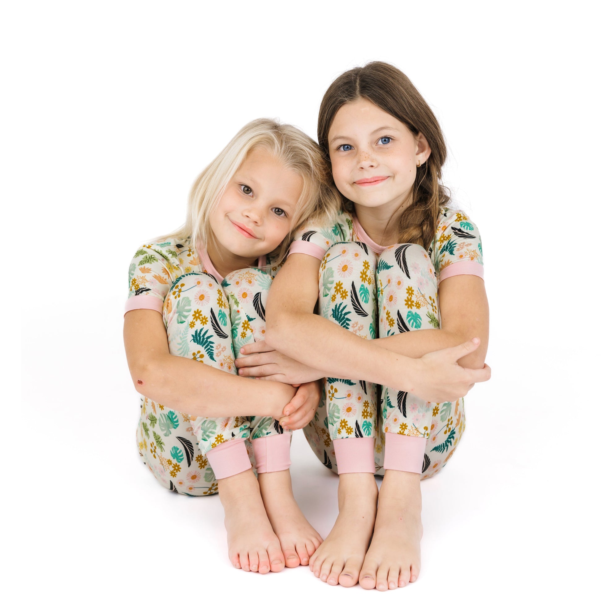 Two young girls sitting together in soft, temperature-regulating Tropical Blooms bamboo pajama sets.