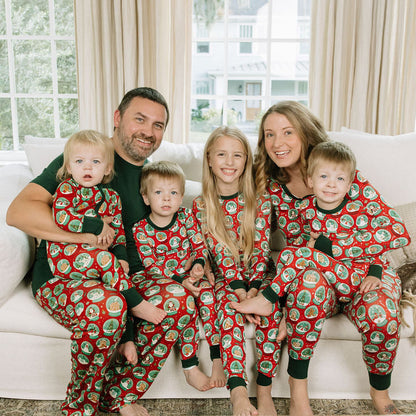 Family of five wearing matching Let It Snow bamboo Christmas pajamas while sitting together on a white couch.