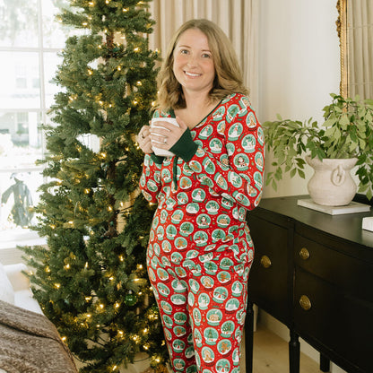 Woman wearing Let It Snow Bamboo Pajama Jogger Pants with a matching holiday pajama top beside a Christmas tree.