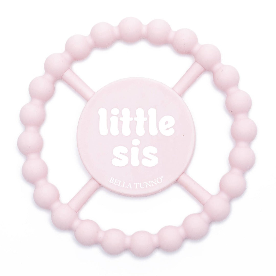 light pink round silicone baby teether that says little sis in white