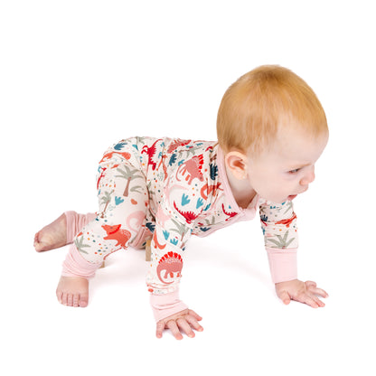 Baby wearing bamboo zip pajama with dinosaur print while crawling