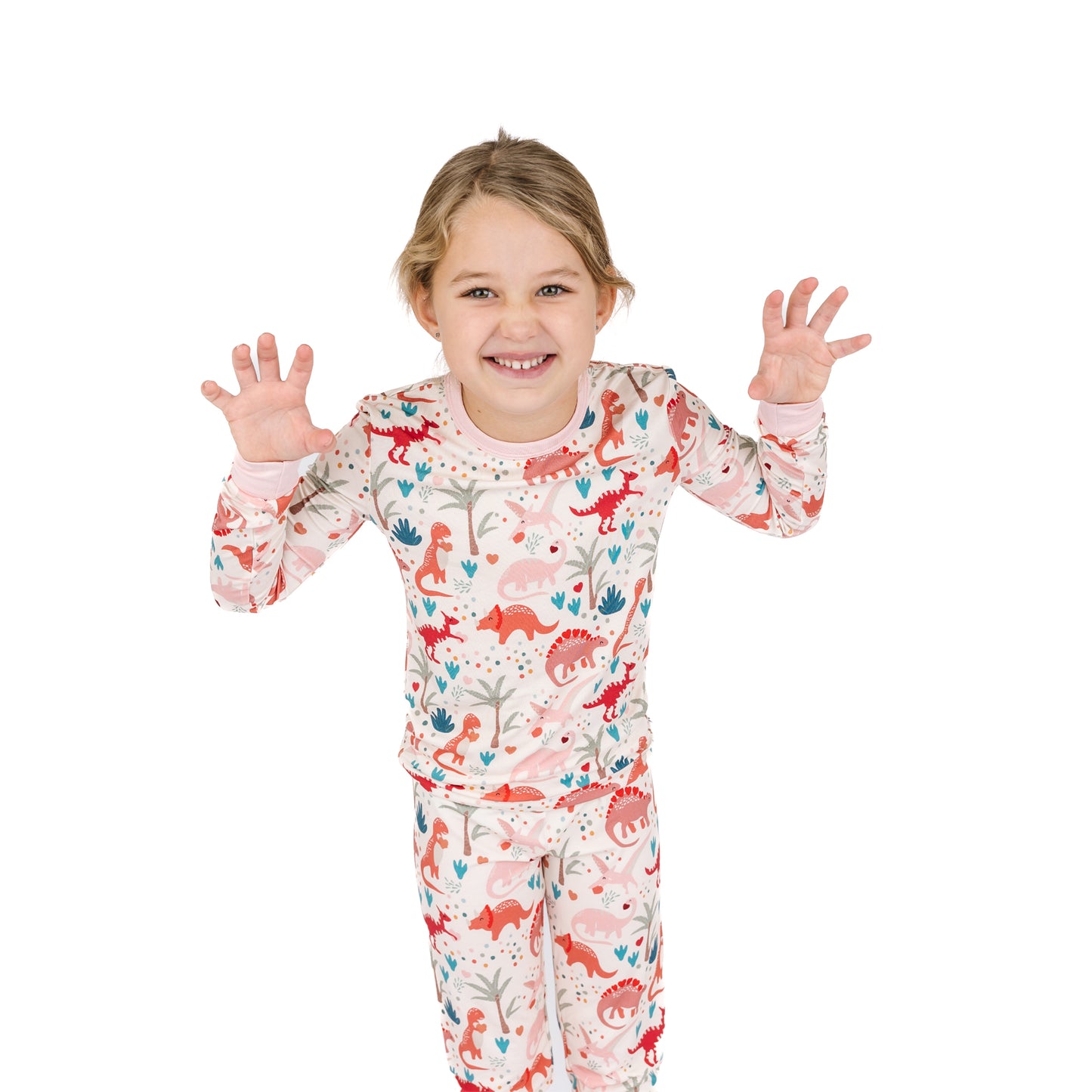 Child wearing Lovasaurus Pink bamboo two-piece pajama set with dinosaur print.