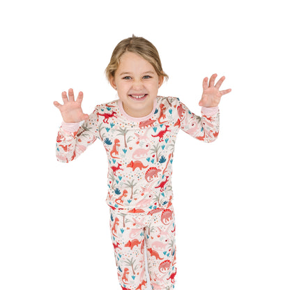 Child wearing Lovasaurus Pink bamboo two-piece pajama set with dinosaur print.