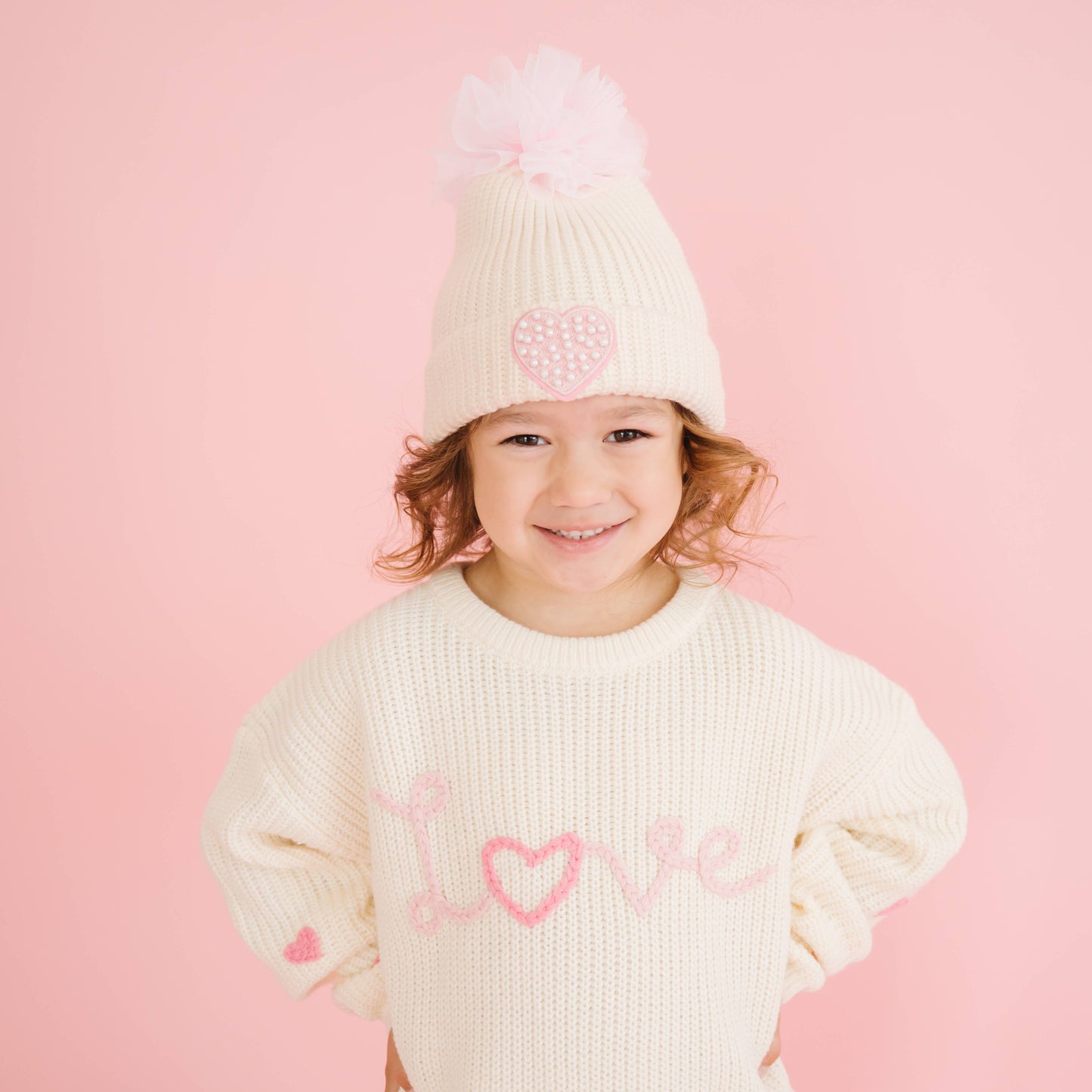 Smiling child wearing Love knit sweater with heart details.