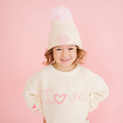 Smiling child wearing Love knit sweater with heart details.