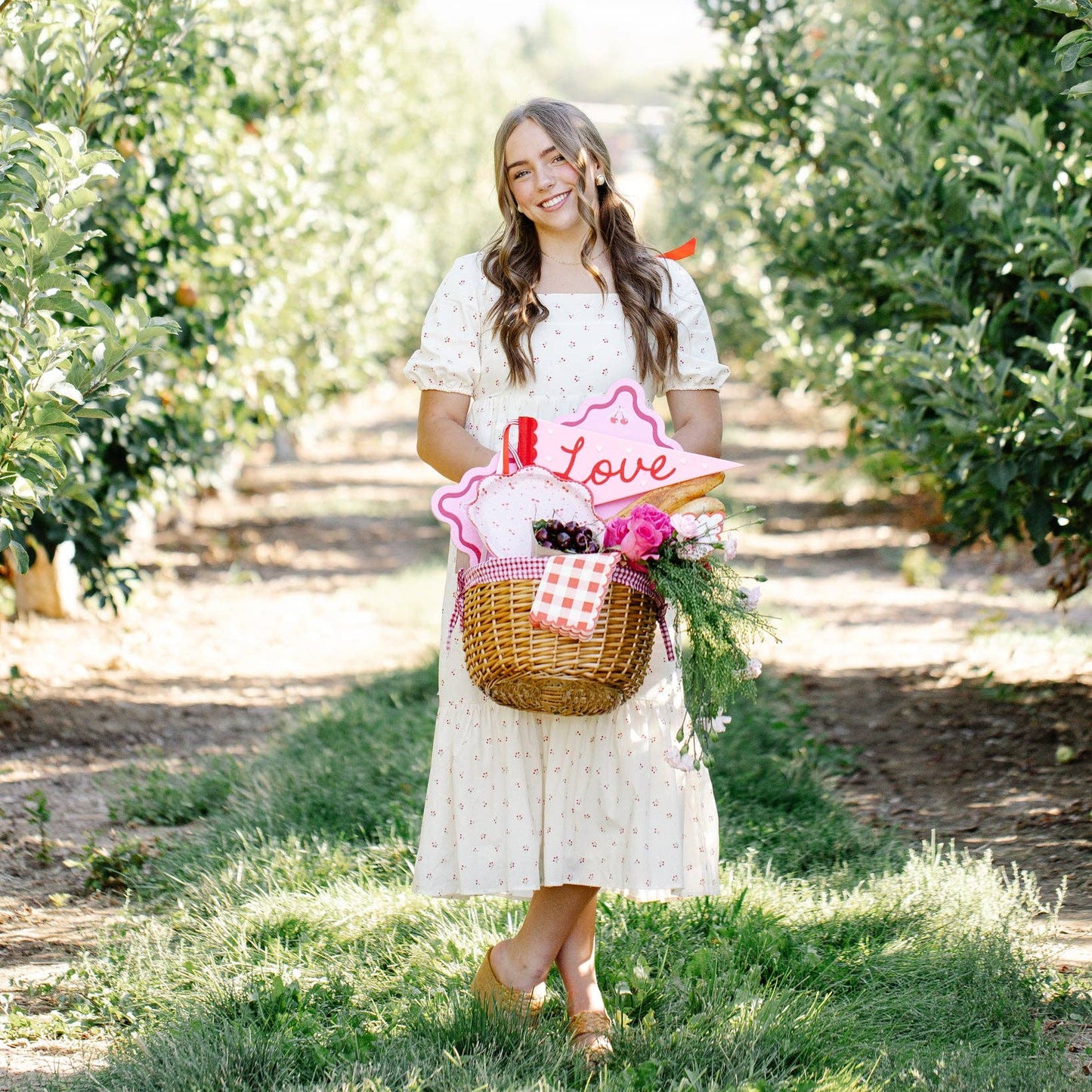 Woman holding a basket with flowers and 'Love' sign in an orchard