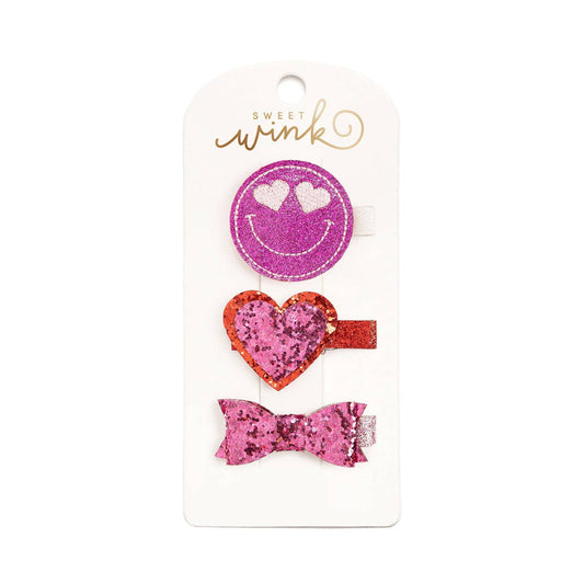 3 pack of valentines day themed hair clips including a purple smiley face, a red and pink heart, and a pink bow