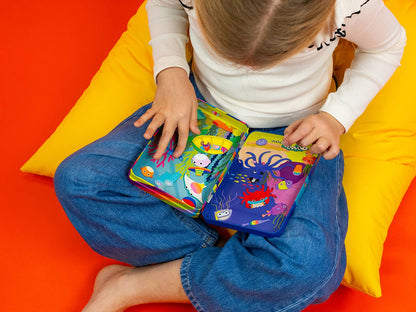 Child sitting on a colorful cushion holding a colorful book