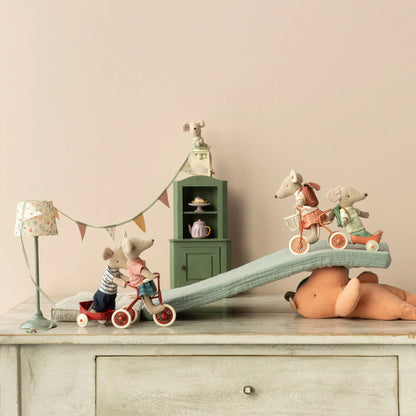 Children's toys on a dresser with a lamp and small cabinet in the background.