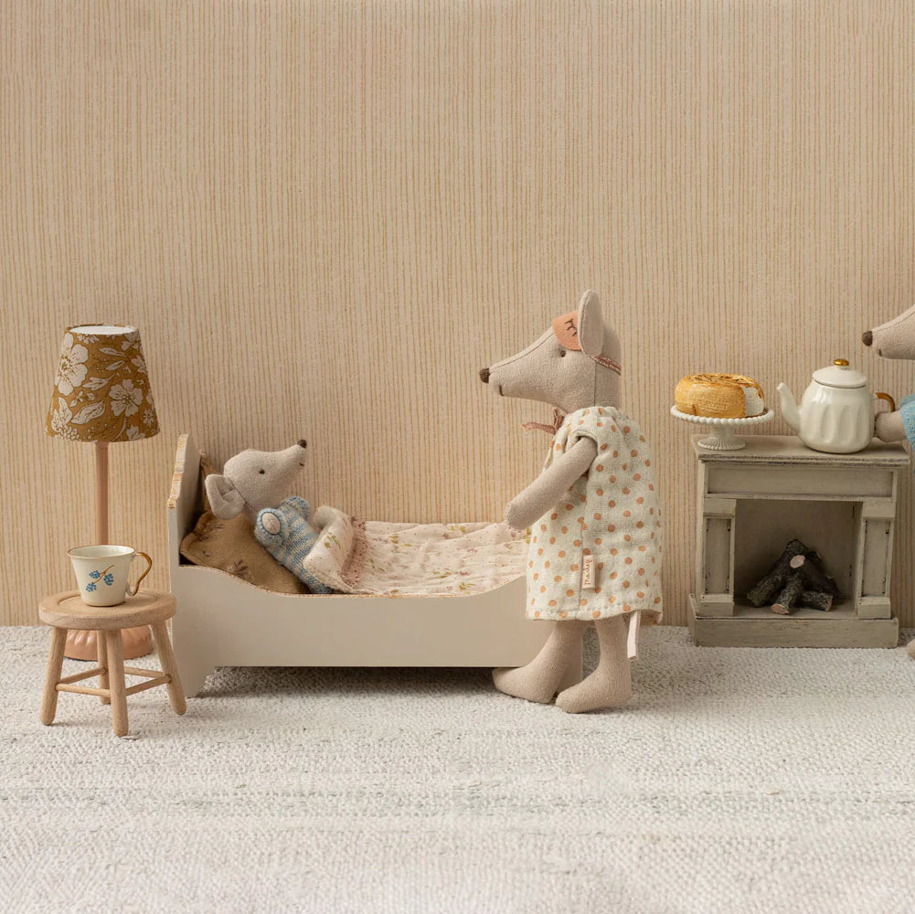 Miniature scene with toy mice in a room setting, including a bed, table, and lamp.
