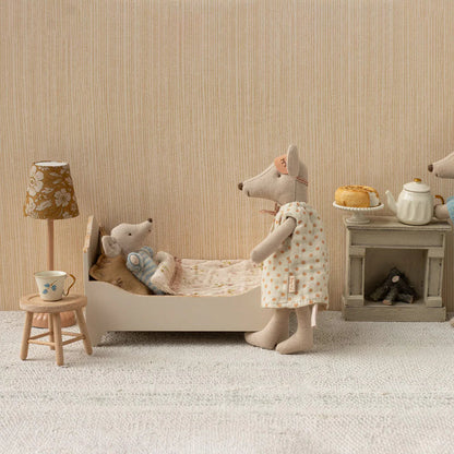Miniature scene with toy mice in a room setting, including a bed, table, and lamp.