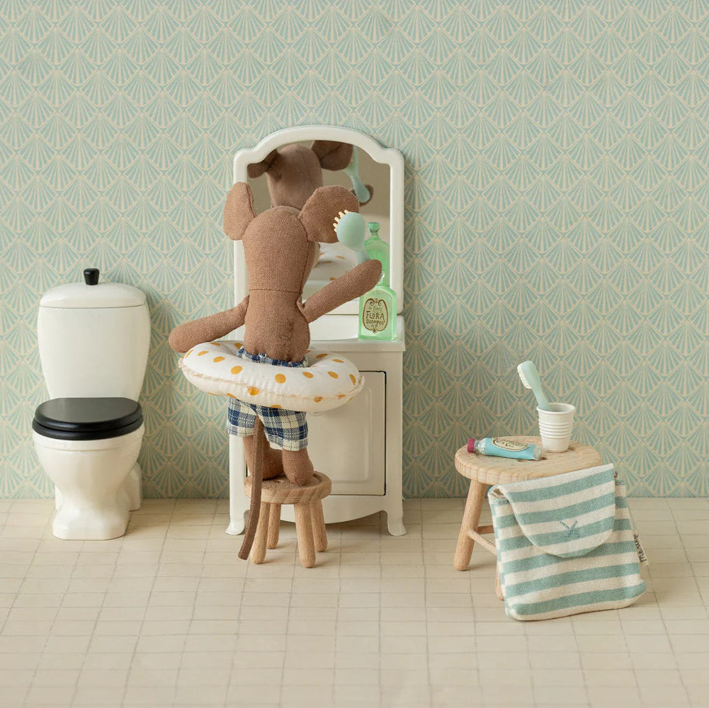 Stuffed teddy bear in a bathtub with bathroom items and wallpaper.