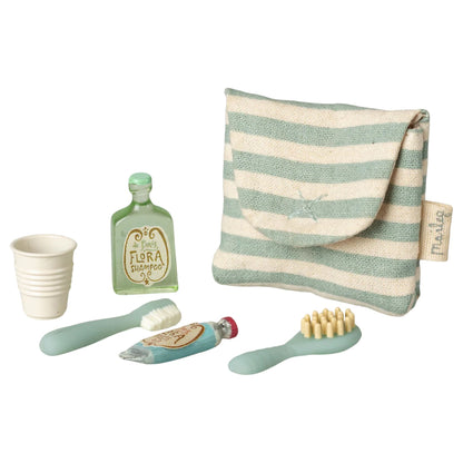 Set of children's bathroom accessories including a striped pouch, cup, bottles, and brushes on a white background.