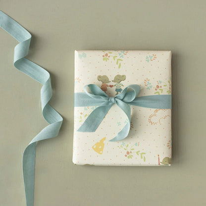 Gift box with floral pattern and blue ribbon on a beige background