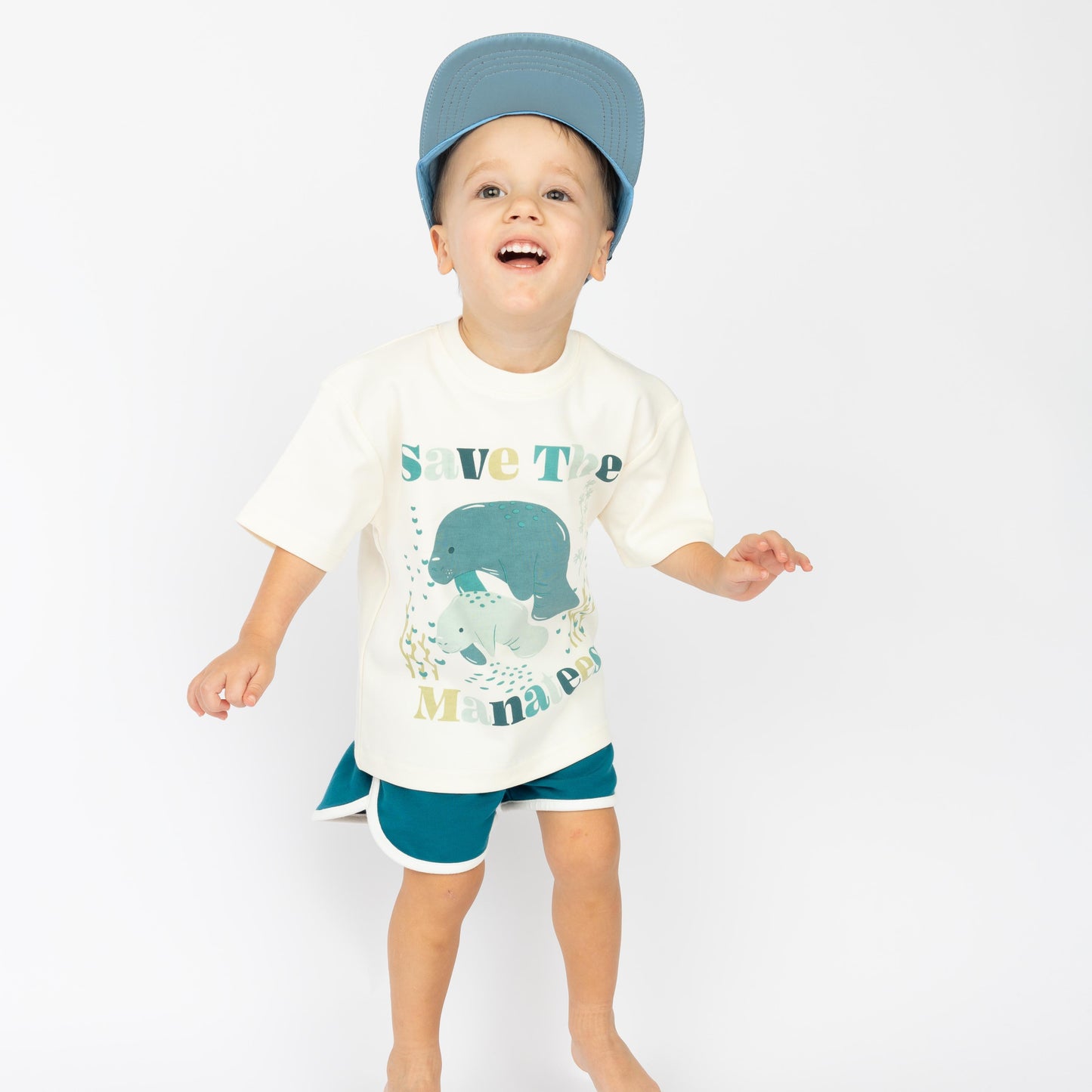 Little boy wearing our Save the Manatees Cotton Toddler Short Sleeve Shirt along with our Save the Manatee Snap Back.