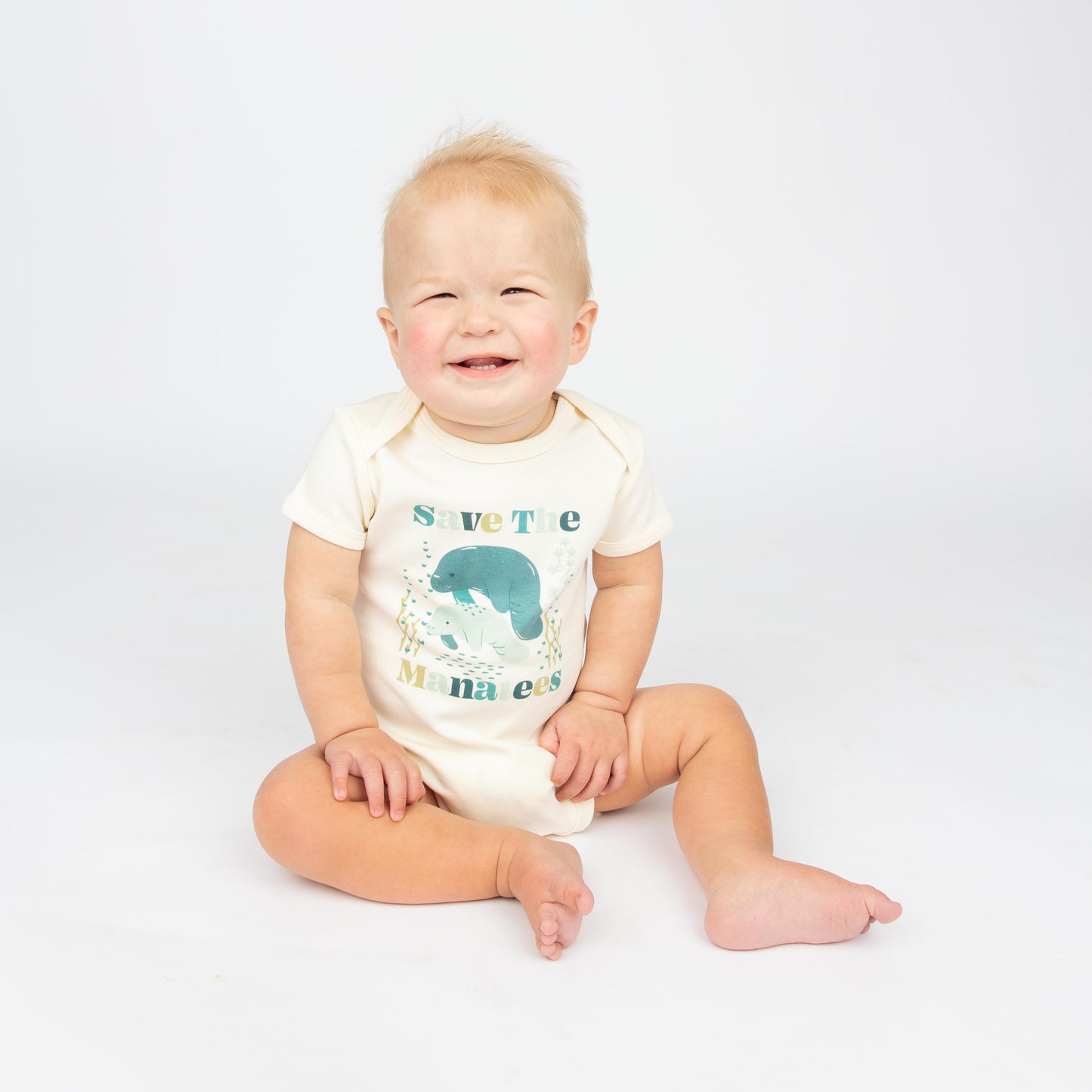 Baby wearing a Save the Manatees cotton onesie with a cute manatee print, featuring soft, eco-friendly fabric on a white background.