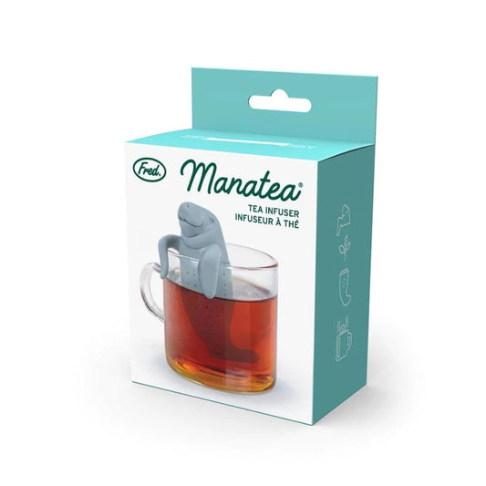 Gray Manatee shaped tea infuser in a glass of tea on a blue and white box