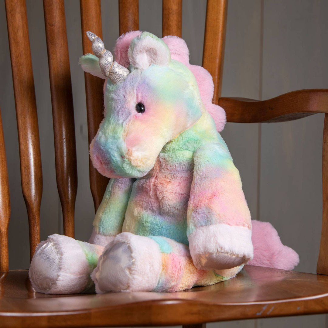 pastel rainbow colored stuffed unicorn toy sitting on a wooden chair