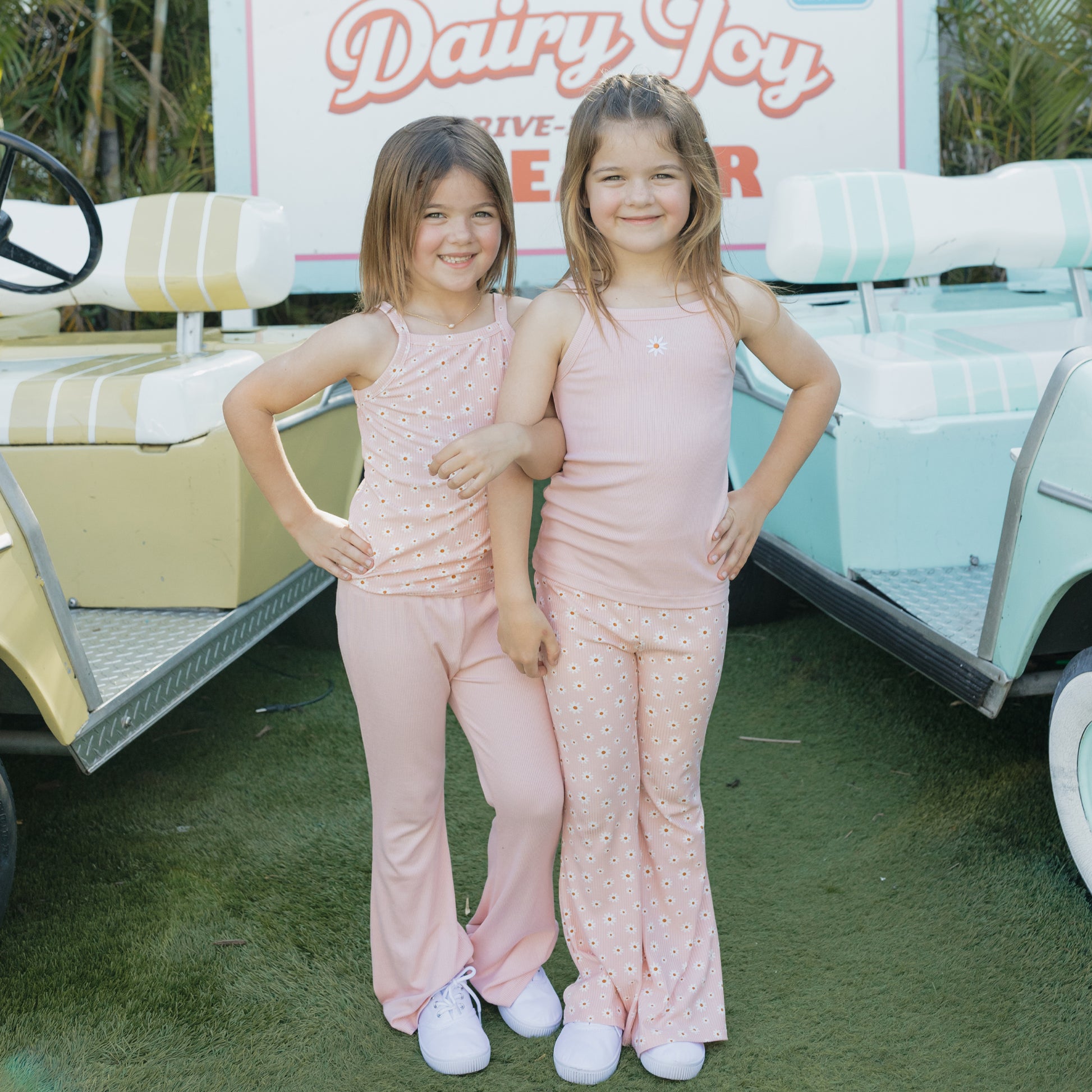 Two young girls in matching pink outfits standing in front of a vintage Dairy Joy ice cream truck.