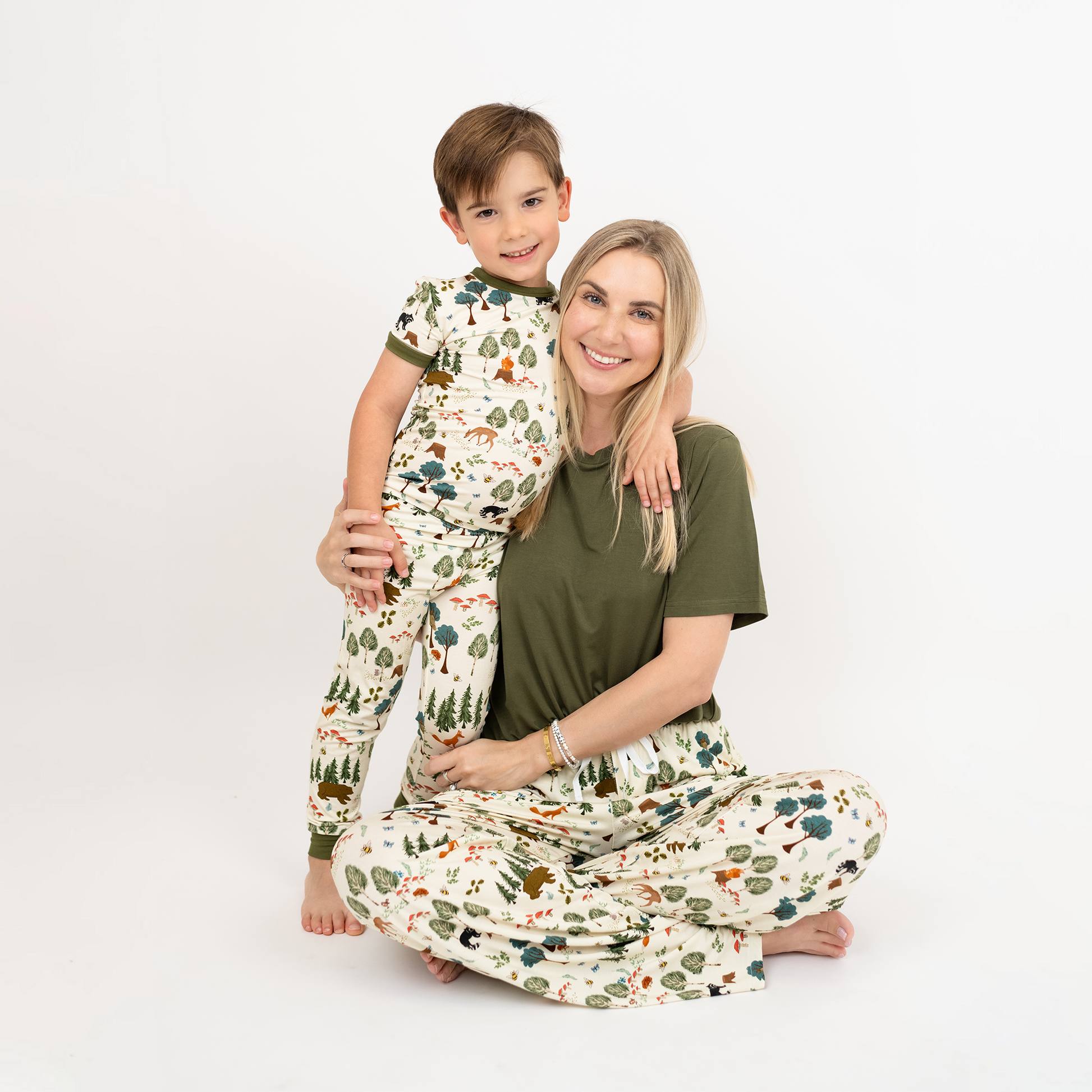 Woman and child wearing In the woods matching pajamas with a nature print on a white background