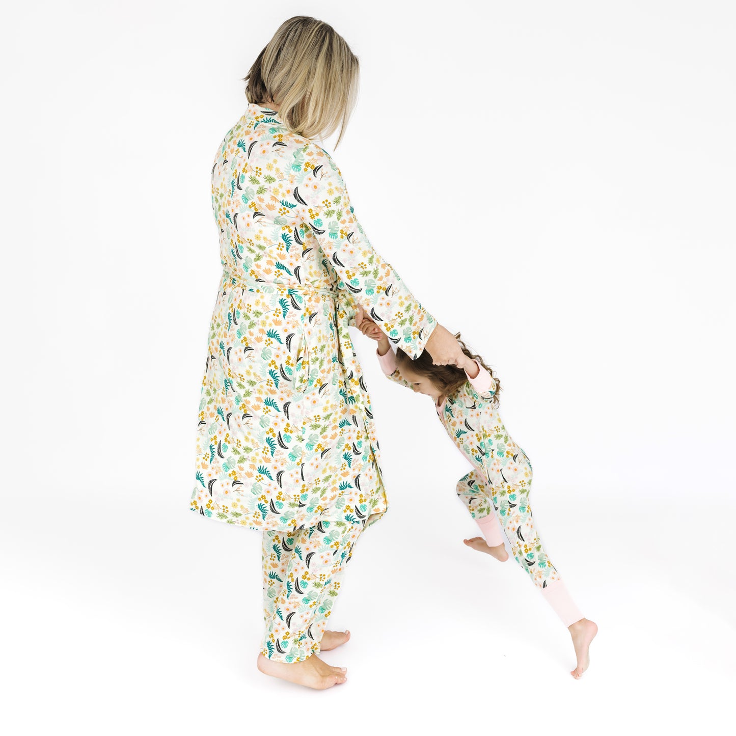 A mother wearing the Tropical Blooms luxury robe while coordinating with her children in matching botanical print styles.