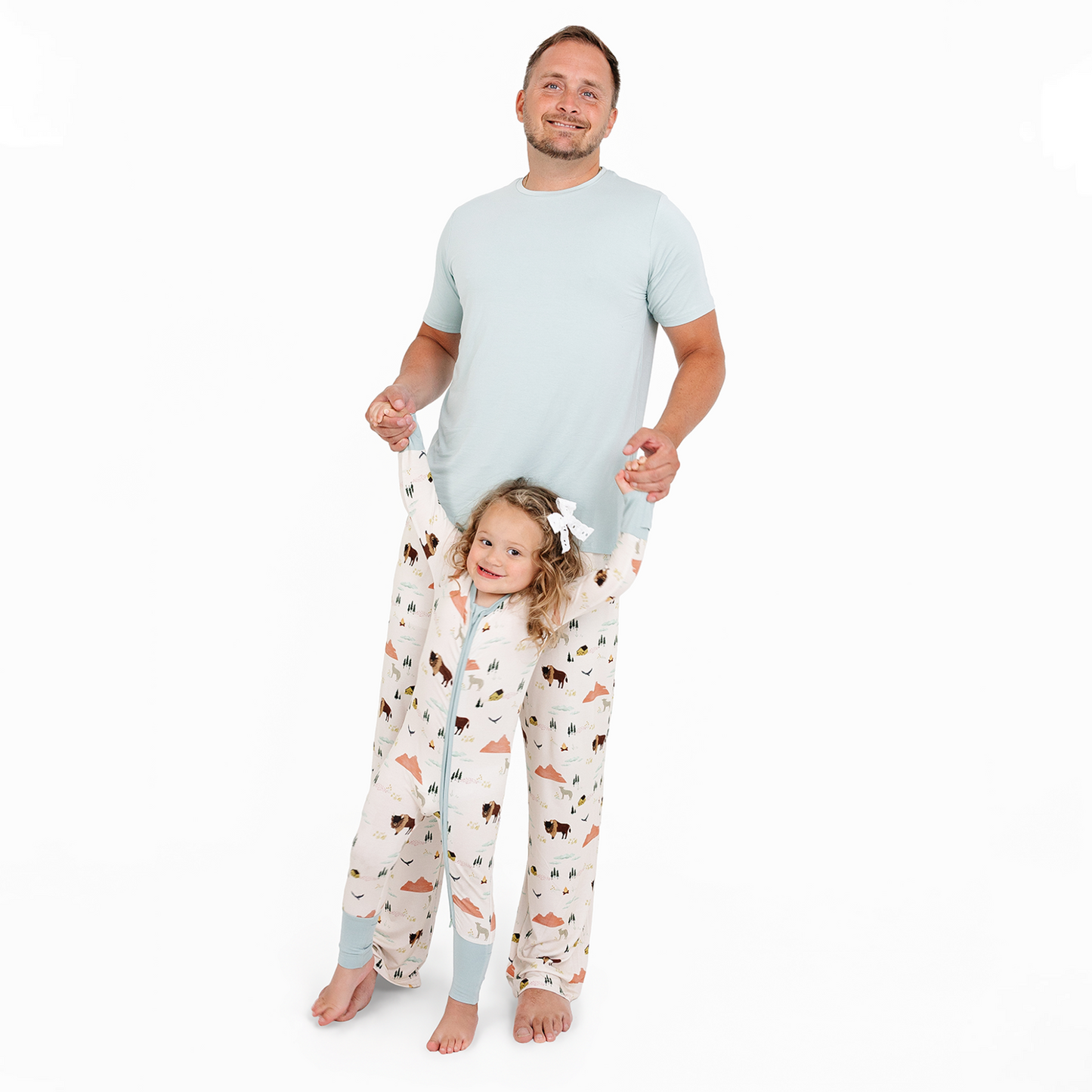 Man and child wearing matching pajama sets with animal print on a white background