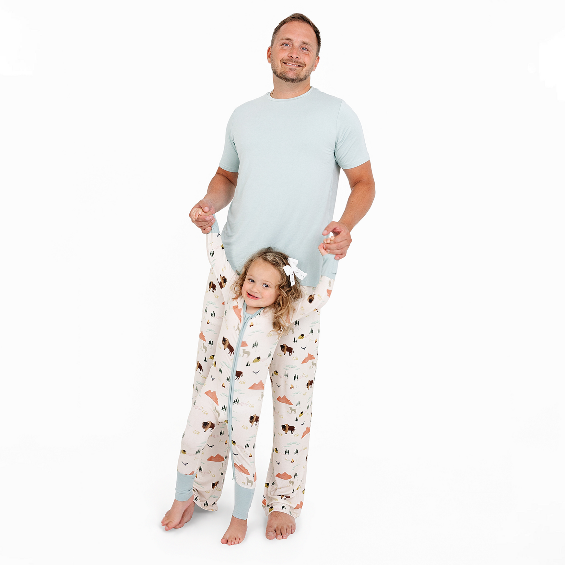 Man and child wearing matching pajama sets with animal print on a white background