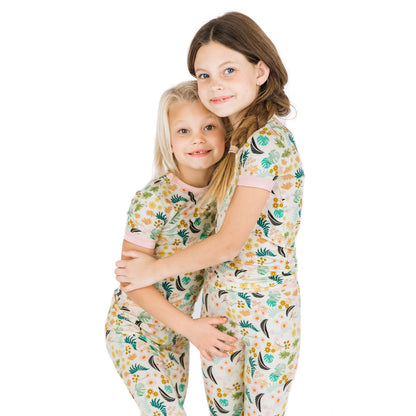 Two sisters hugging while wearing matching Tropical Blooms botanical print bamboo pajamas.