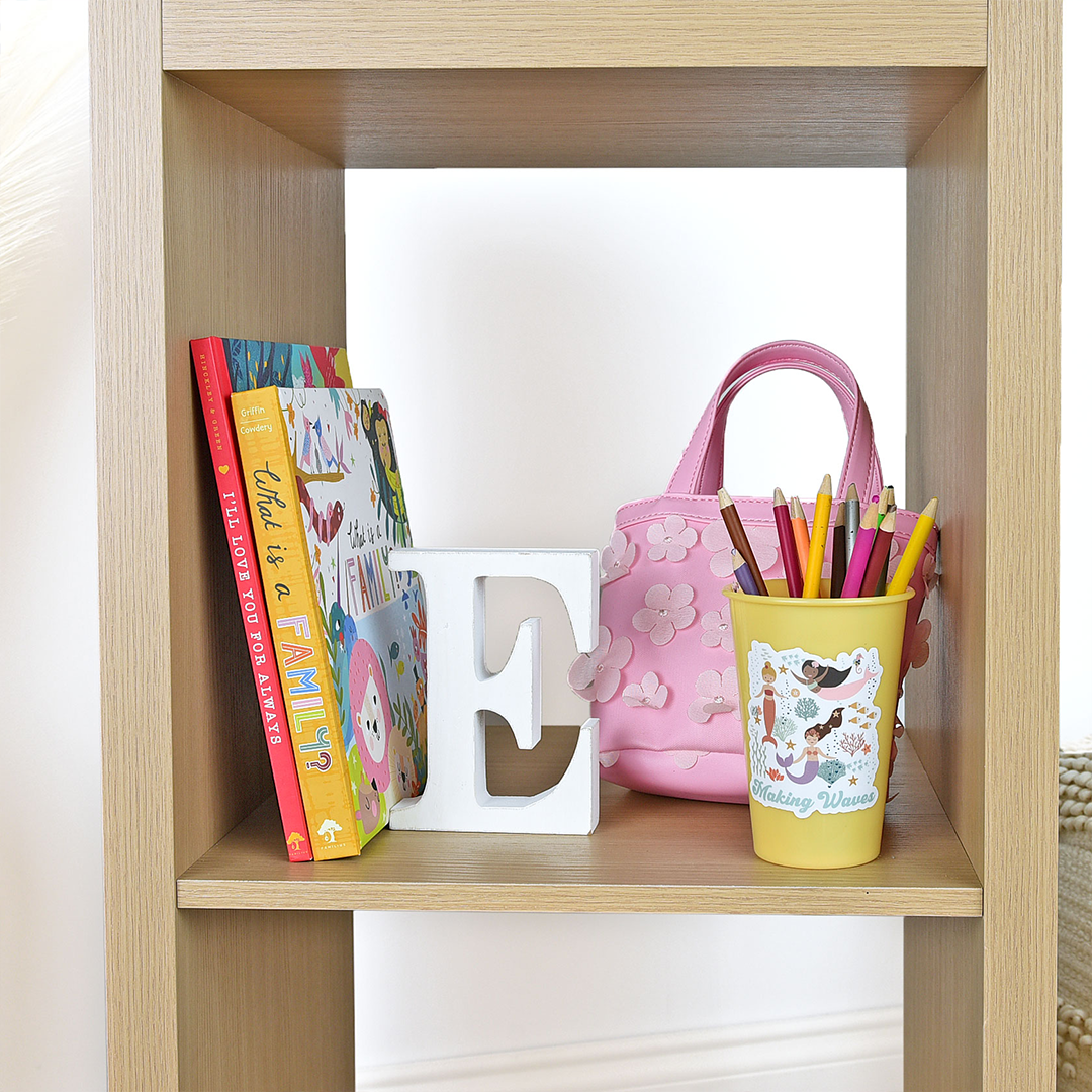 a pencil cup is on a shelf. the "making waves" sticker is stuck to the cup. 