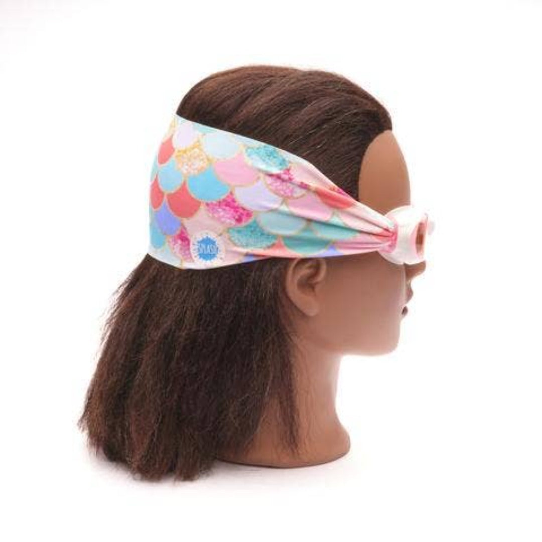 Pink swim goggles with mermaid scales on the strap on a female mannequin head