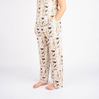 someone poses with their hands in the "making waves" relaxed pants. the "making waves" print has a diverse spread of mermaids, sea coral, starfish, fish, and bubbles all spread out in different colors. this is all put on a beige background.