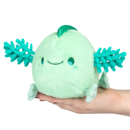 Light green plush toy with teal leaves held in a hand on a white background