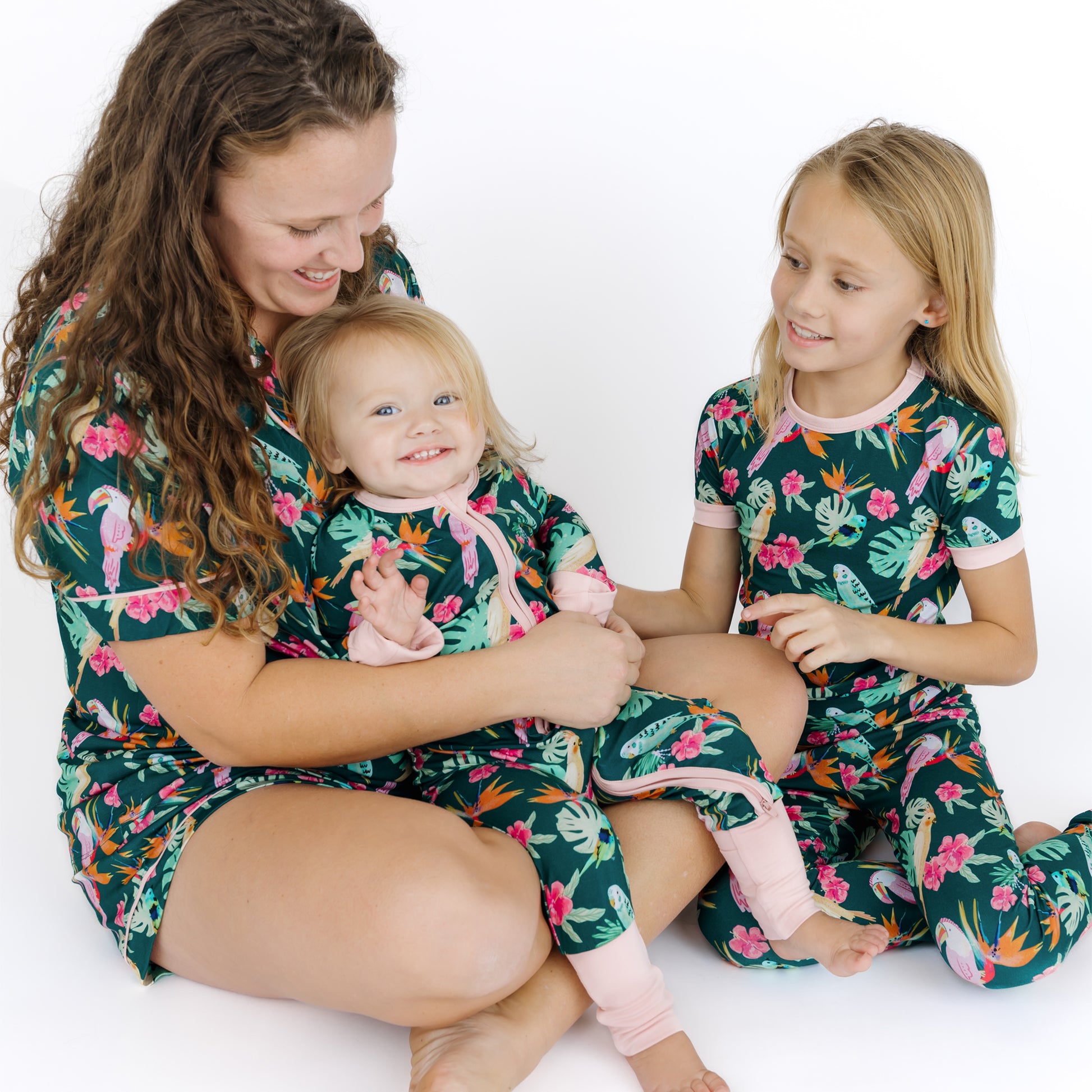 A mother and children wearing matching Isla Botánica tropical print pajamas, perfect for coordinated family style.