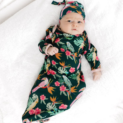 A newborn baby laying down in the Isla Botánica bamboo tie gown and hat set, perfect for hospital or first photos.