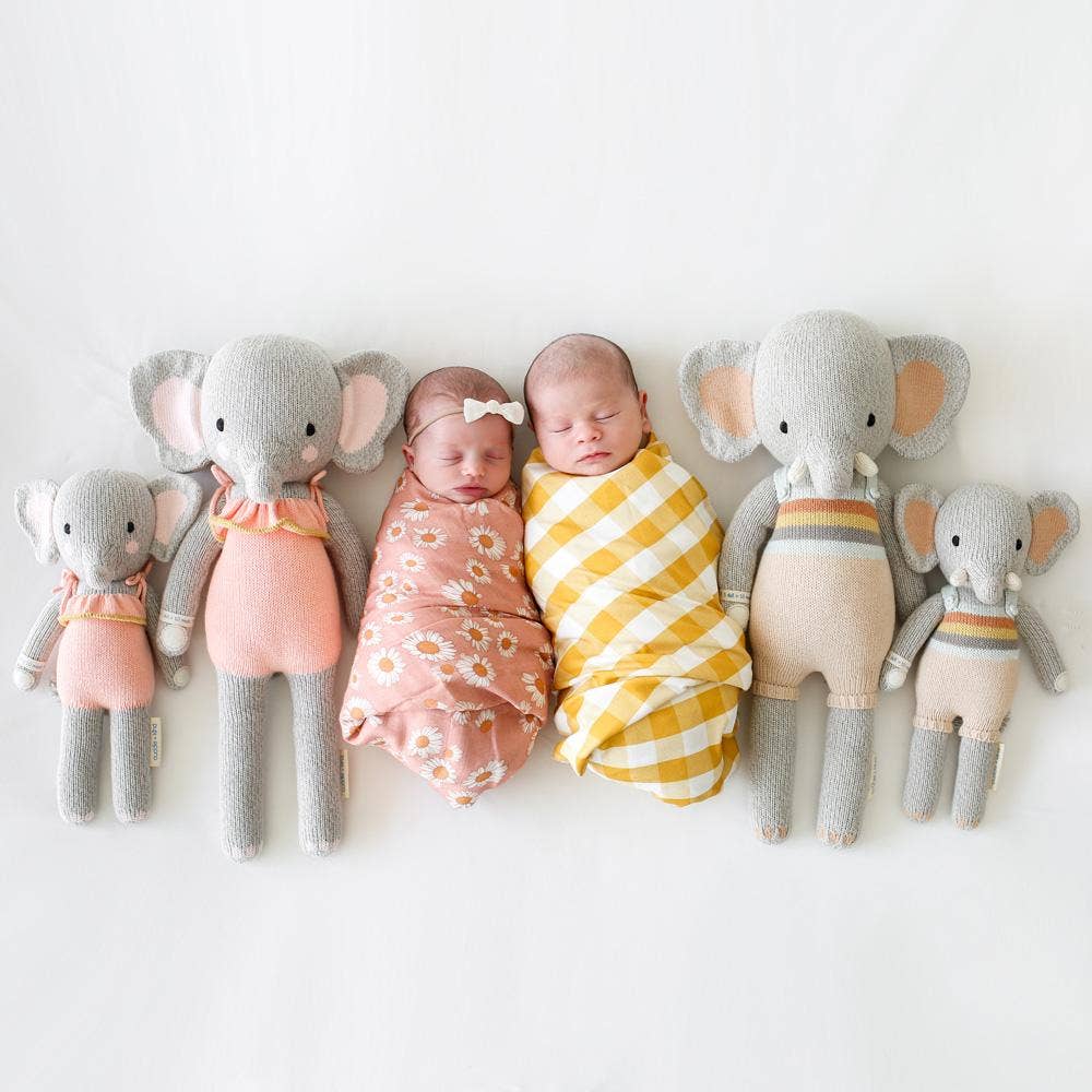 Two swaddled babies flanked by four elephant plush toys on a white background