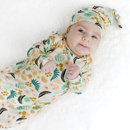 A sleeping newborn baby wearing the soft Tropical Blooms bamboo gown and hat set, perfect for hospital photos.