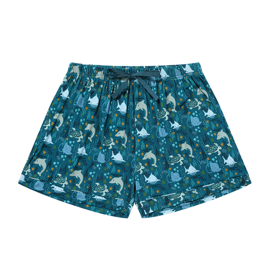 the "ocean friends" women's shorts. the "ocean friends" print is a combination of dolphins, stingrays, fish, starfish, coral, bubbles, and sharks, all spread out on a deep sea blue background. 
