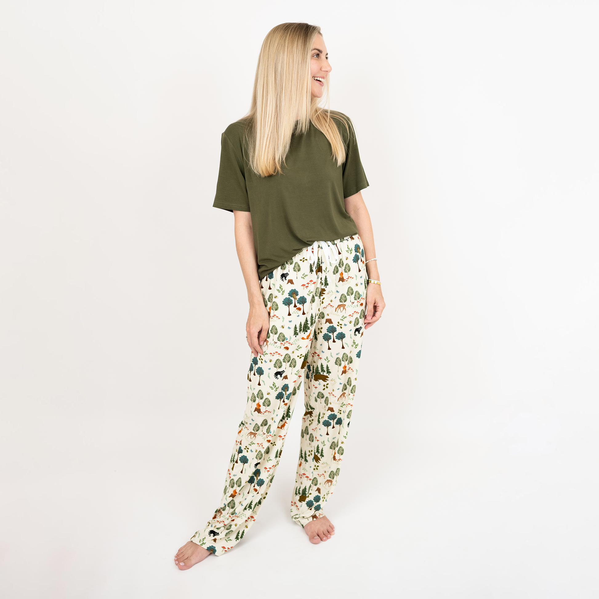 Woman wearing a green top and our In the Woods pants on a white background
