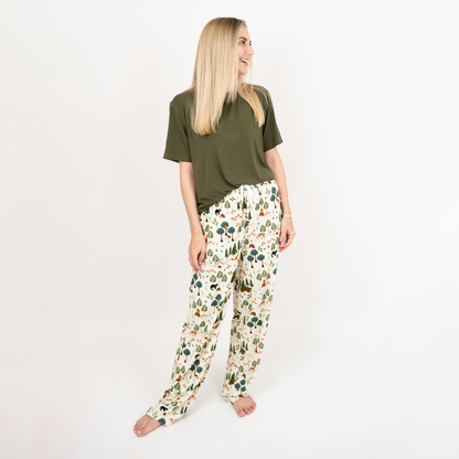 Woman wearing a green top and our In the Woods pants on a white background