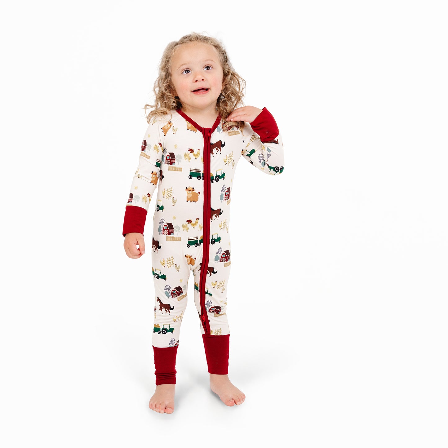 Child in On the Farm bamboo convertible pajamas with barnyard animals, tractor, and cow print.