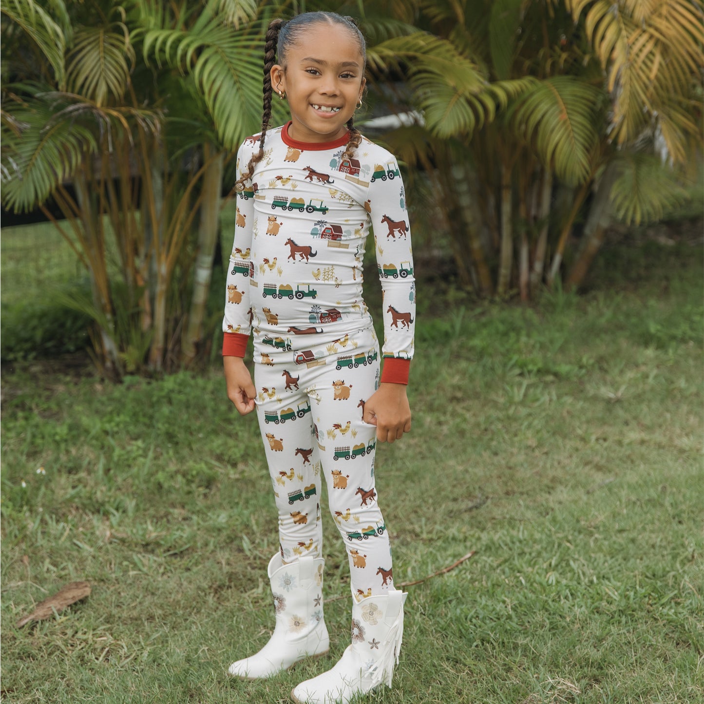 Child wearing On the Farm bamboo kids pajama pants set with horse, tractor, and cow barnyard print.