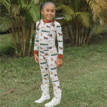 Child wearing On the Farm bamboo kids pajama pants set with horse, tractor, and cow barnyard print.