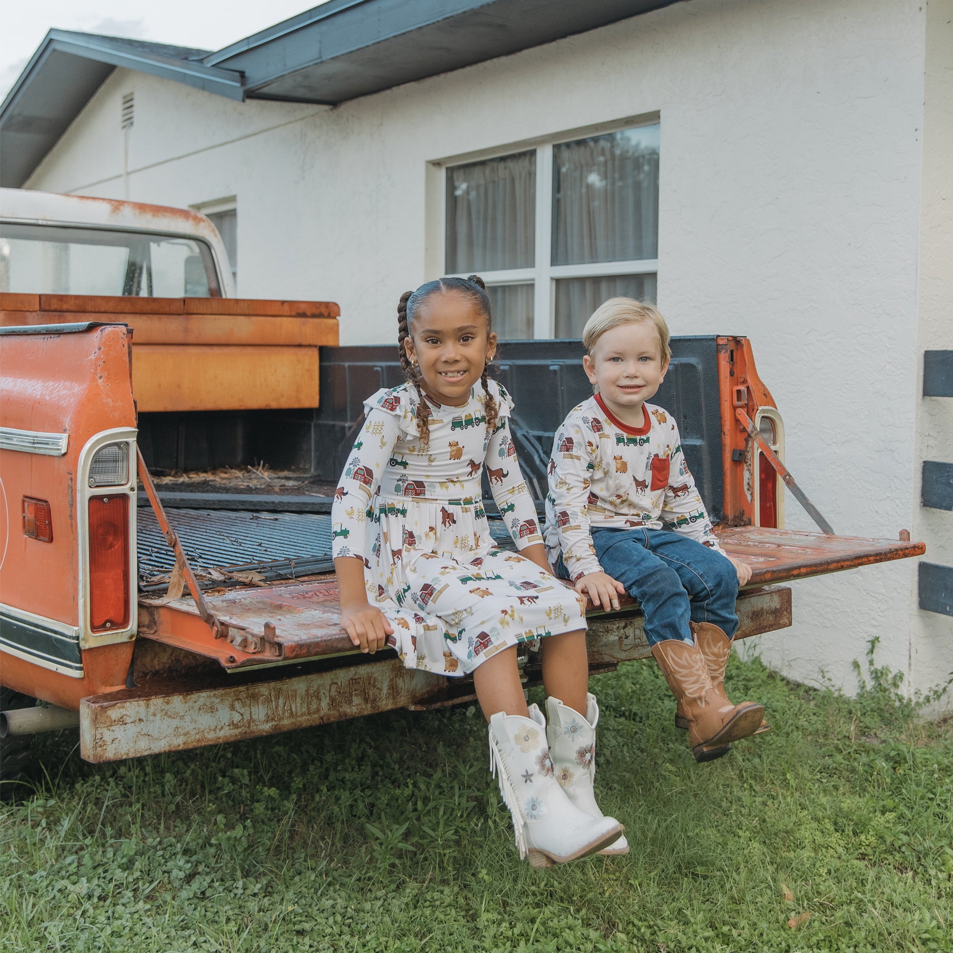 Two siblings in matching On the Farm  animal print, soft, breathable, and hypoallergenic for sensitive skin.