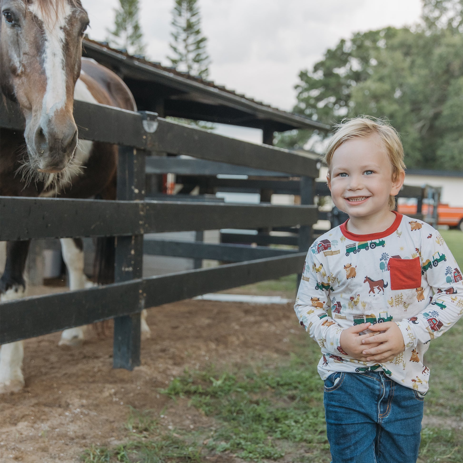 Child wearing On the Farm bamboo pocket tee with tractor and horse print, soft, breathable, and hypoallergenic fabric for sensitive skin.