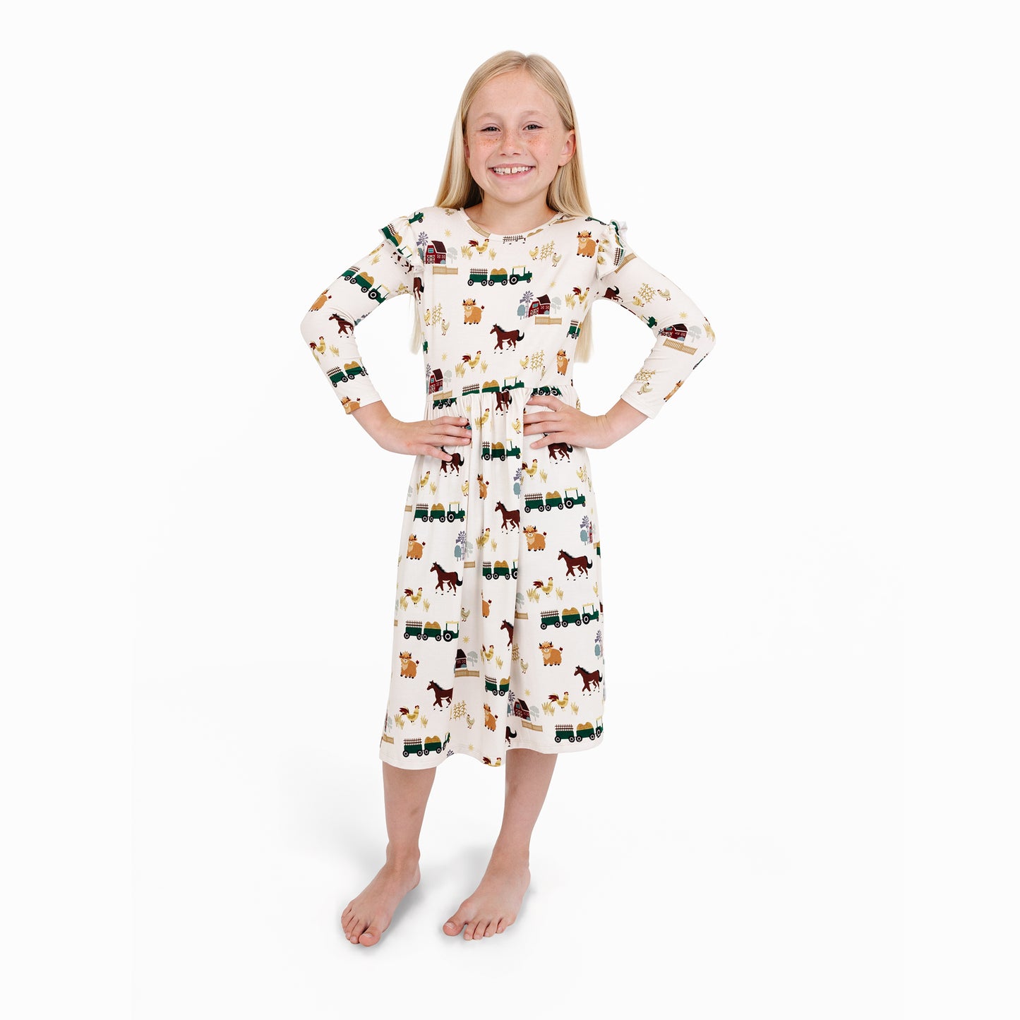 Child in On the Farm bamboo ruffled long sleeve twirl dress with horse and tractor print, soft and breathable for sensitive skin.
