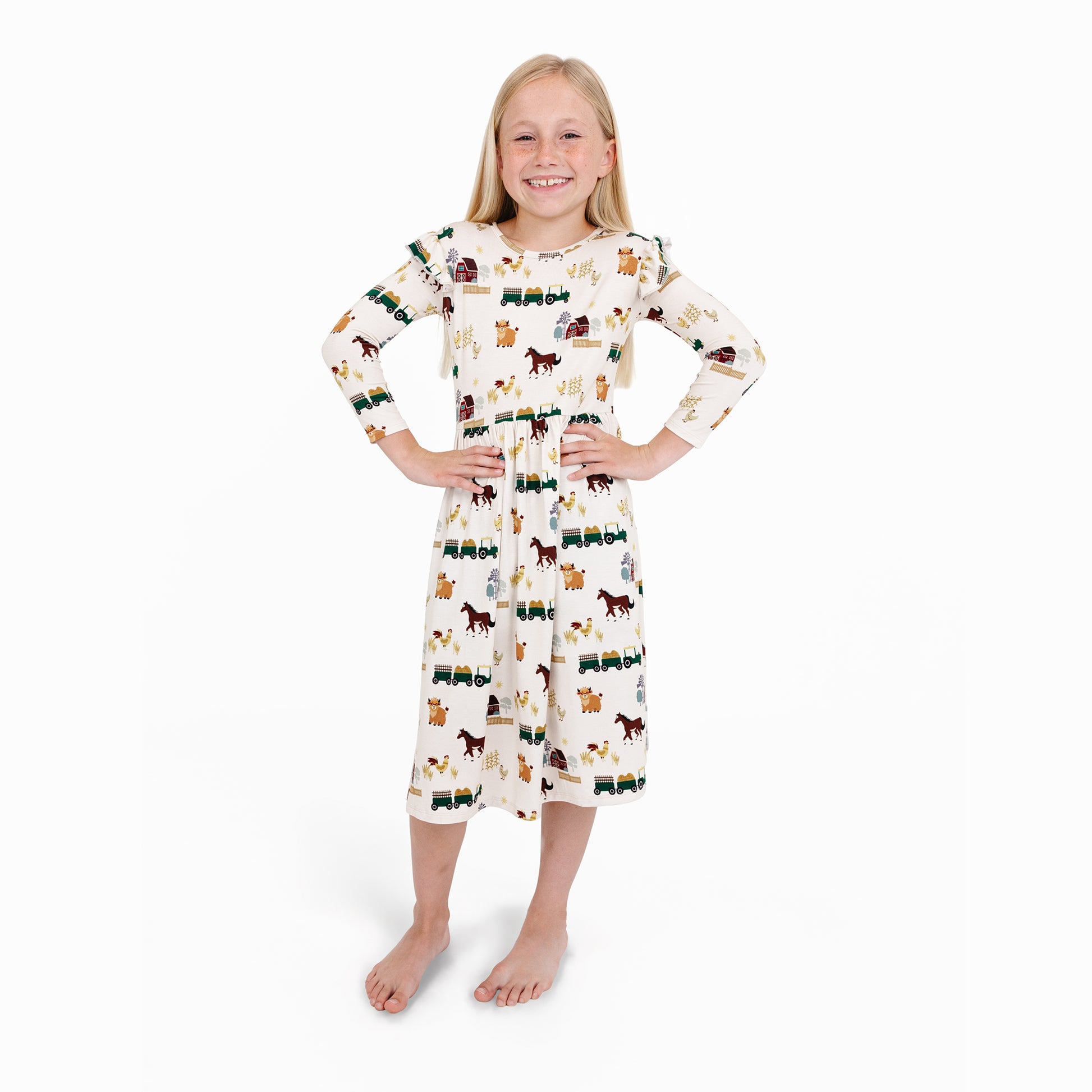 Child in On the Farm bamboo ruffled long sleeve twirl dress with horse and tractor print, soft and breathable for sensitive skin.